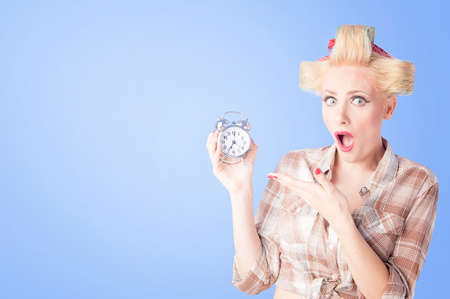 Blonde girl looking surprised on vintage alarm clockの写真素材