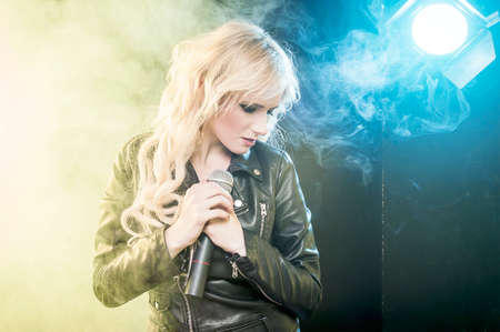 Young beautiful woman singing in colourful smokeの写真素材