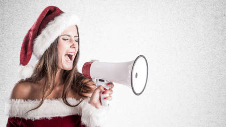 Woman wearing a Santa Claus costume and holding a megaphoneの写真素材
