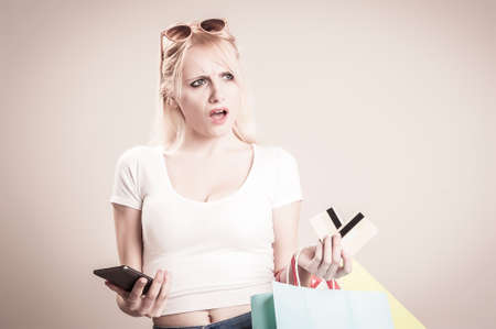 Young  girl with shopping bags surprised at mobile phoneの写真素材