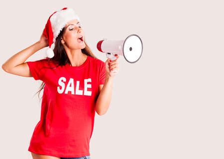 Woman wearing a Santa Claus hat and wearing a sale message t shirt holding a megaphoneの写真素材