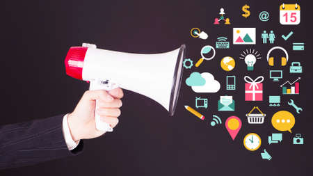 Businessman hand with loudspeaker with symbols flying outの写真素材