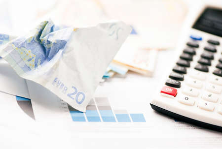 Crumpled Euro banknotes with calculator and chartsの写真素材