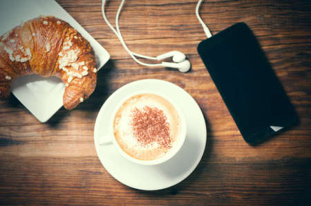Cappuccino croissant and mobile phoneの写真素材
