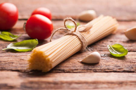 Spaghetti and tomatoes with herbs on an old and vintage wooden tableの写真素材