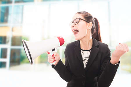 Young pretty businesswoman yelling over megaphone.の写真素材