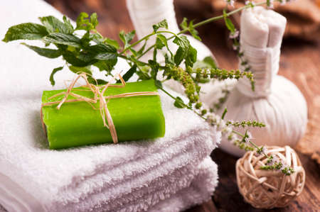 Bars of soap with fresh mint leaves and towels on wooden tableの写真素材