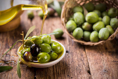 Bottle pouring virgin olive oil in a bowl close upの写真素材