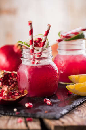 Cold transparent pomegranate drink on a wooden background. Selective focus.の写真素材