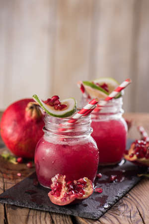 Cold transparent pomegranate drink on a wooden background. Selective focus.の写真素材