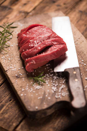 Raw beef steak on a dark wooden table.の写真素材