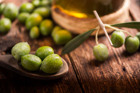 Green olives on a wooden spoonの写真素材