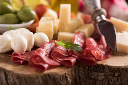 Assorted deli meats and a plate of cheese, on a wooden cutting board. Italian antipastiの写真素材