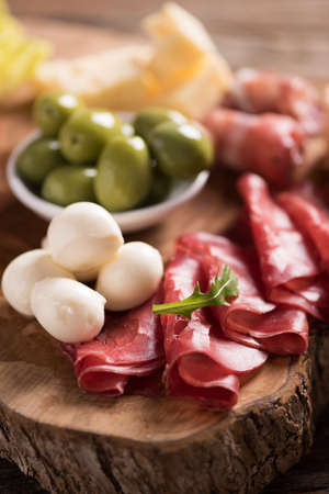 Assorted deli meats and a plate of cheese, on a wooden cutting board. Italian antipastiの写真素材