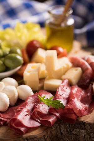 Assorted deli meats and a plate of cheese, on a wooden cutting board. Italian antipastiの写真素材