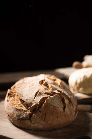 Freshly baked bread on wooden table on dark background