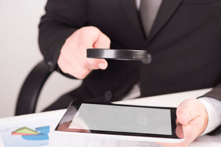 Businessman checking a tablet with magnifying glass の写真素材