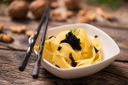 caviar pasta tagliatelle on a white bowl with wooden back ground. Close upの写真素材