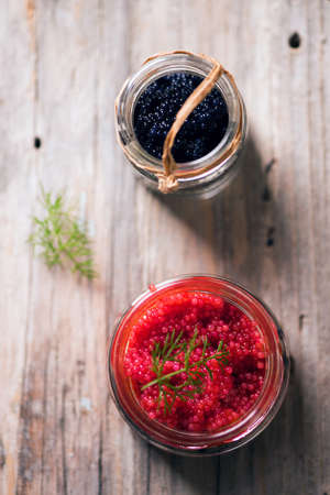 red and black caviar  in jars on a wooden table backgroundの写真素材
