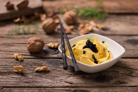 caviar pasta tagliatelle on a white bowl with wooden back ground. Close upの写真素材