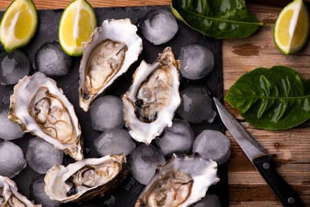 Oysters on stone black plate with ice and lemonの写真素材