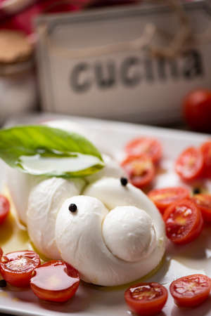 Braid of mozzarella served with tomatoes on a white plate with wood background