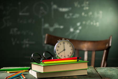 8 am Back to school concept. Alarm clock on books with blackboard on backgroundの写真素材