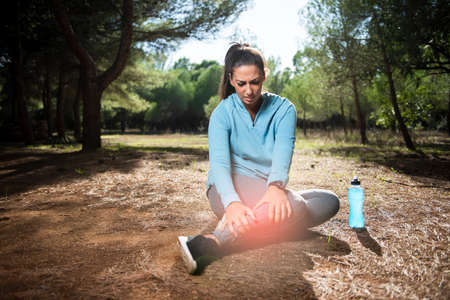 Runner sport knee injury. Woman in pain while running in the park.