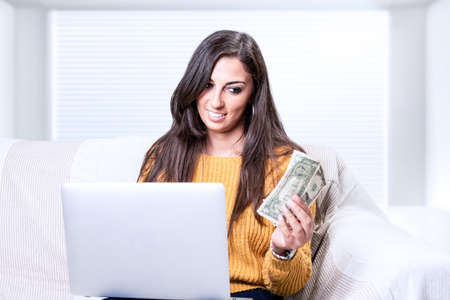 A successful young business woman holding money dollar bills in handの写真素材