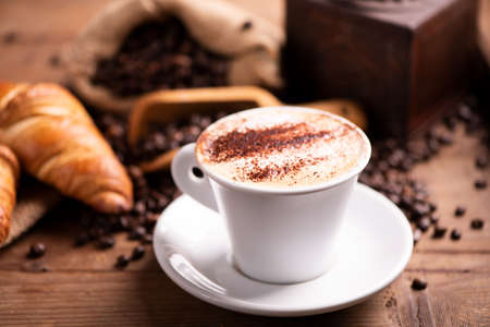 Cappuccino coffee over dark roasted coffee beans close upの写真素材