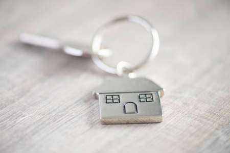 House keys on a house shaped keychain  on wood background concept for real estate