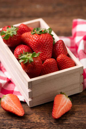 Fresh strawberries in a basket on old wooden table close upの写真素材