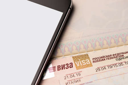 Fragment of a visa of the Russian Federation in the passport  with mobile phone close up