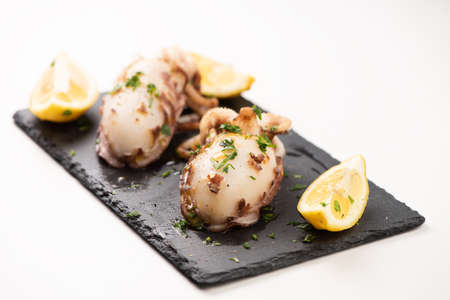 Delicious BBQ cuttle fish on a stone dish isolated on whiteの写真素材