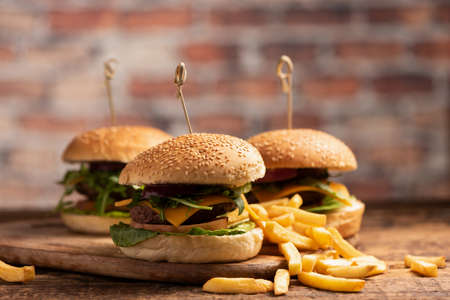 A juicy grilled hamburger with lettuce, cheddar cheese, onions, tomato  on wood boardの写真素材