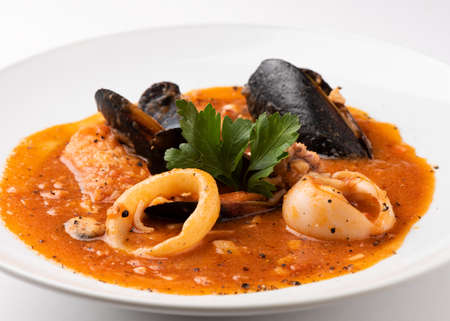 Fish soup with seafood, prawns, mussels and squid in a tomato sauce over a whiteの写真素材