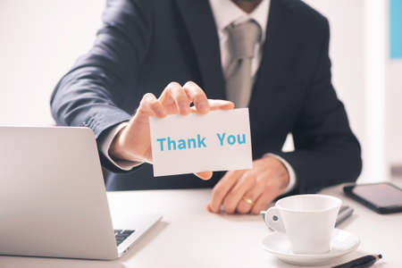 Business man holding a card with thank you text close upの写真素材