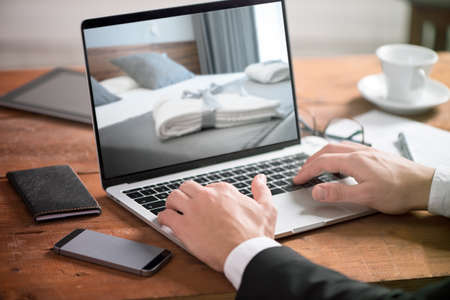 Buisiness man hand on table using a laptop with hotel room bookingの写真素材