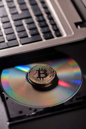 Golden Bitcoin currency with blockchain concept on laptop cd rom. Close up