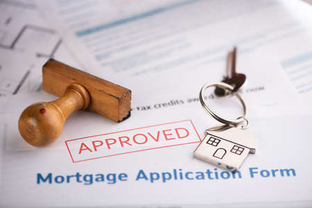 An approved Mortgage loan application form with house key and rubber stamp close up