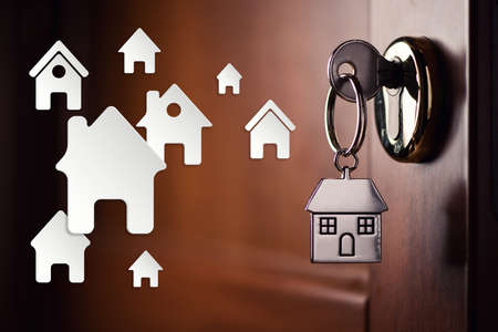 House key on a house shaped silver keyring in the lock of a door