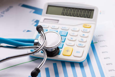 Medical practice financial analysis charts with stethoscope and calculator. Close upの写真素材