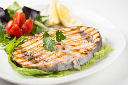 Grilled swordfish with salad and lemon on the white plate. Close upの写真素材