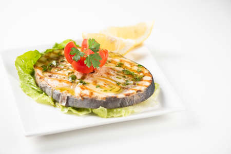 Grilled swordfish with salad and lemon on the white plate. Close upの写真素材