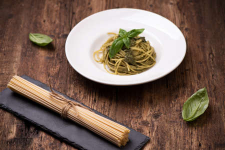 Spaghetti Pesto alla Genovese on rustic wooden table close upの写真素材