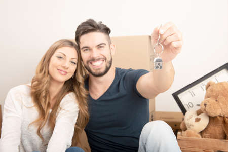 Young smiling couple holding their new house keys, real estate and relocation conceptの写真素材