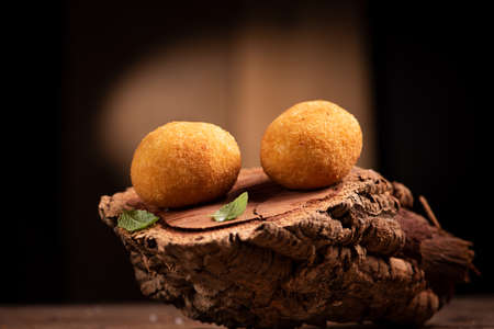 Arancini rice balls. Fried rice balls on brown wooden background. Snack, street food close upの写真素材
