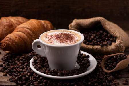 Cappuccino and croissant with coffee beans close upの写真素材