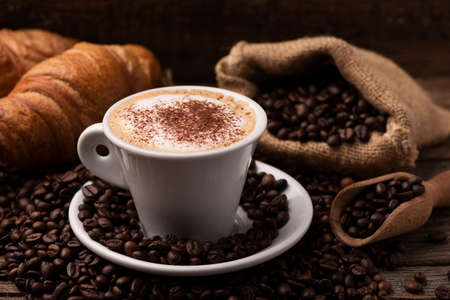 Cappuccino and croissant with coffee beans close upの写真素材
