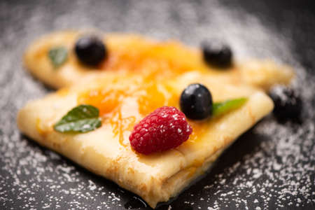 Close up of crepes with powdered sugar and jam  on a plateの写真素材